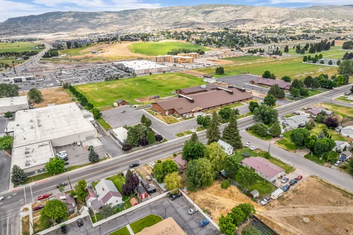 Expansive aerial perspective showcasing diverse property types, surrounding green spaces, and a mountain backdrop