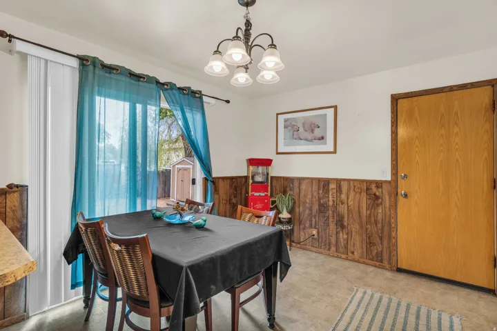 Dining area featuring wood-finish wainscoting, a light-colored door, and a sliding glass door