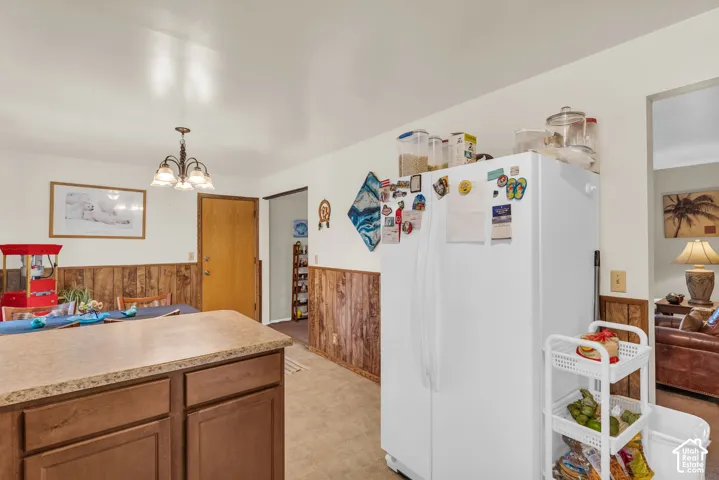 Kitchen area featuring a wood-finish island with a stone-finish countertop, wood paneling, and a four-light chandelier