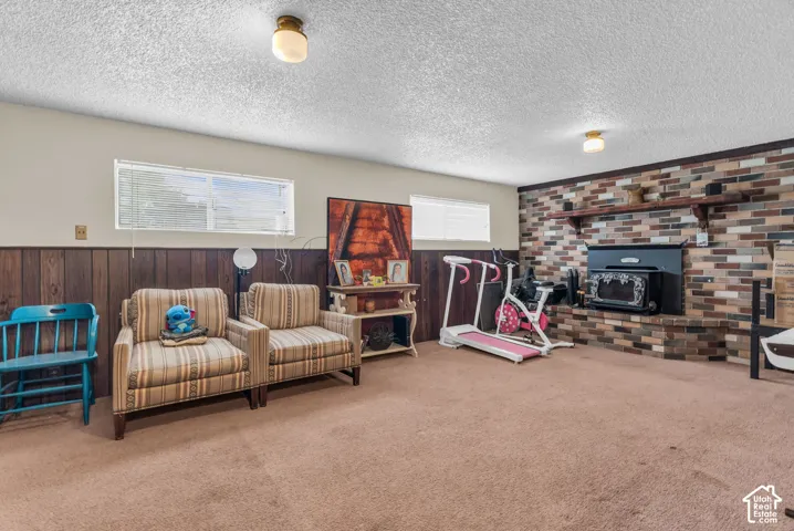 Recreation room featuring a brick accent wall with a built-in fireplace, wood paneling, and a neutral carpeted floor