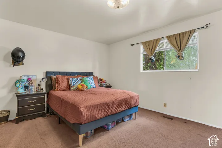 Carpeted bedroom featuring neutral walls and a window with horizontal blinds