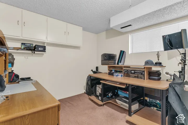 Room featuring a window with blinds, overhead cabinetry, and textured ceiling