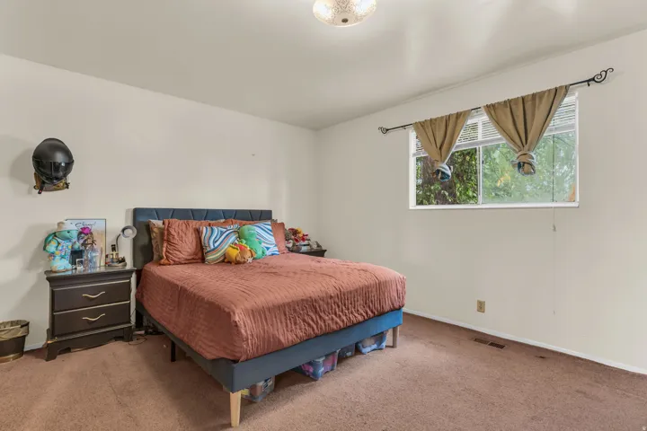 Carpeted bedroom featuring neutral walls and a window with horizontal blinds