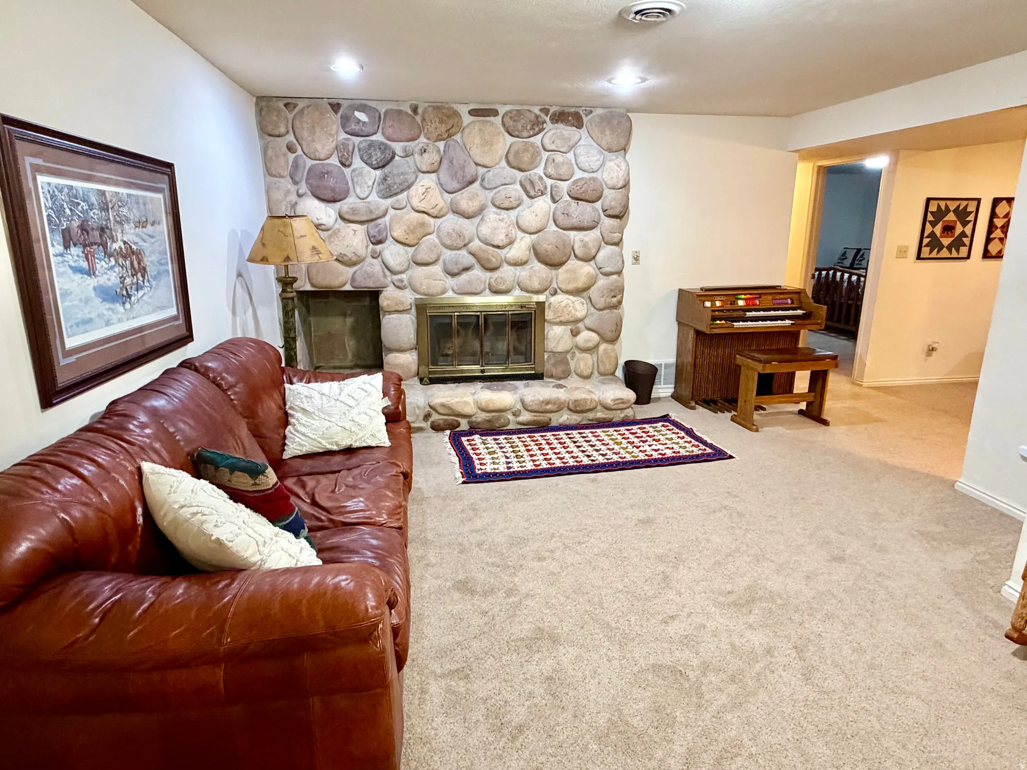 Spacious interior featuring a stone-clad fireplace with a brass firebox, recessed lighting, and carpeted flooring