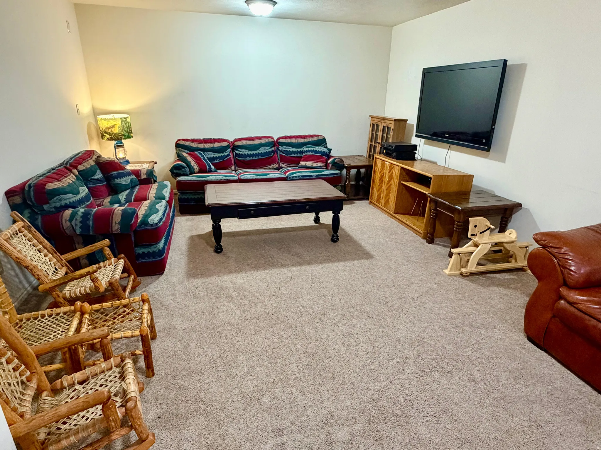 Carpeted living area featuring light-colored walls and a ceiling-mounted light fixture
