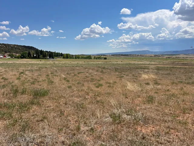 Expansive undeveloped land featuring natural terrain with distant mountain formations and a clear sky