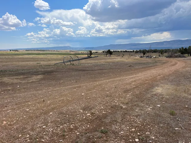 Expansive rural landscape featuring a wide dirt path and distant mountain ranges