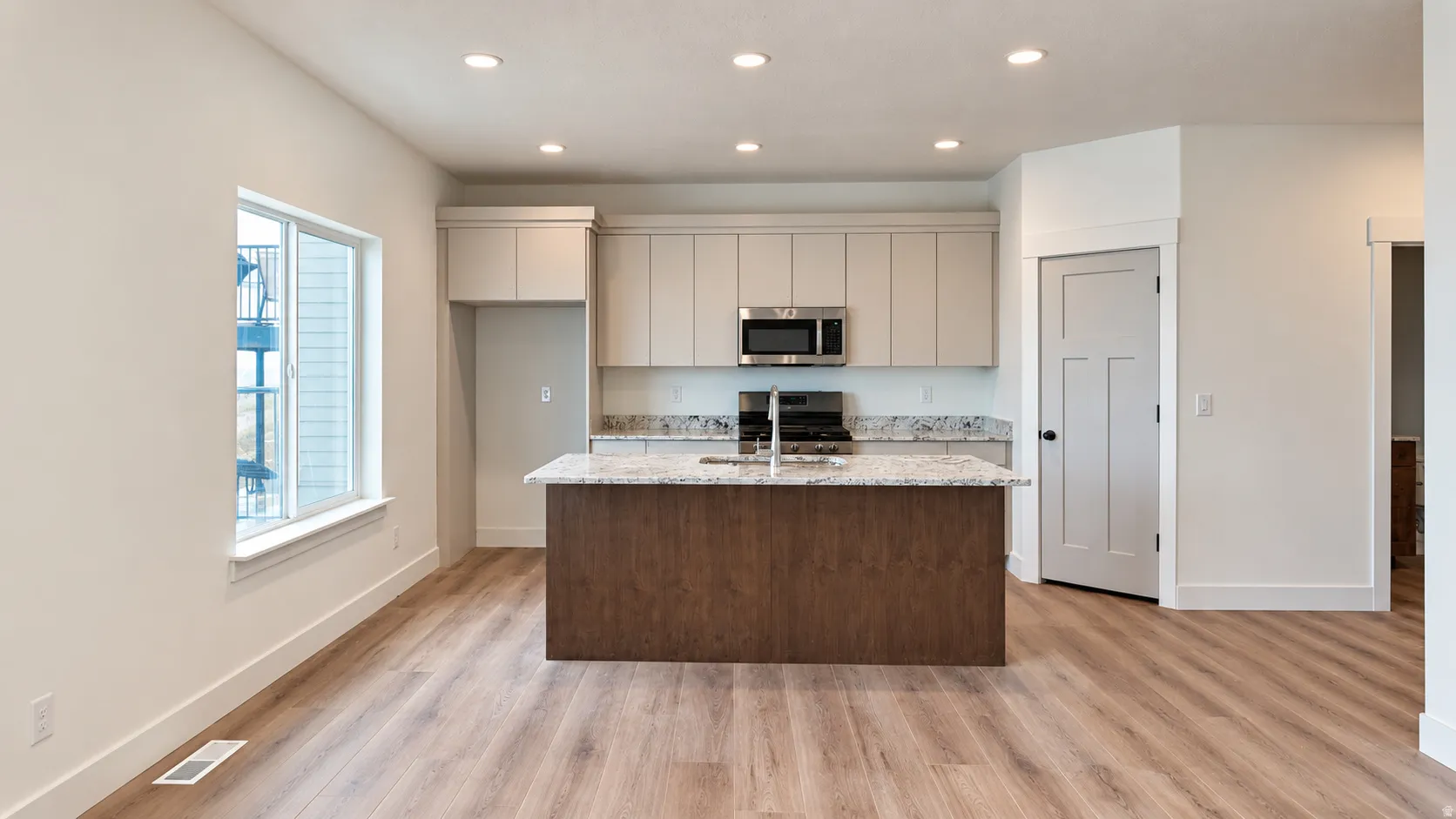 Kitchen featuring a central island with a stone countertop, light wood-finish flooring, and recessed ceiling lighting