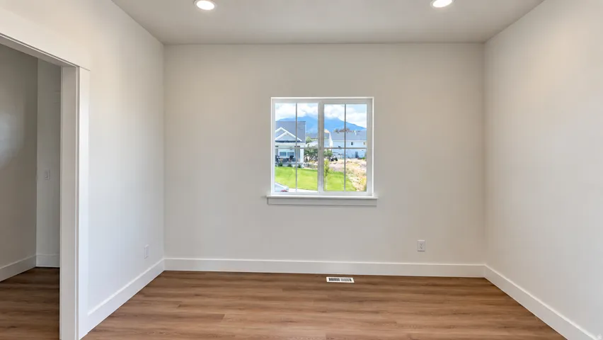 Recessed ceiling lighting, wood-finish flooring, white trim, and a window with mountain scenery