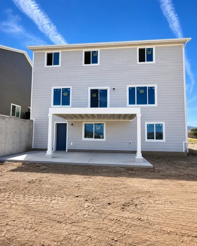 Light gray siding exterior with multiple windows, a covered patio, and a concrete slab