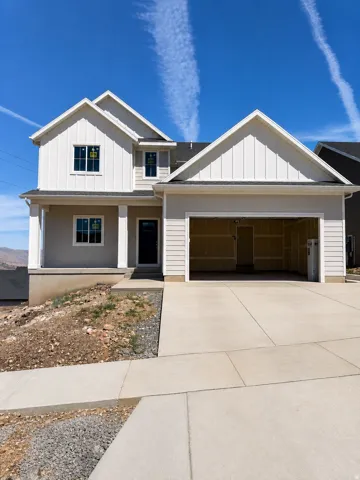Contemporary exterior featuring board and batten siding, multiple gables, a covered front porch, an attached garage, and a concrete driveway