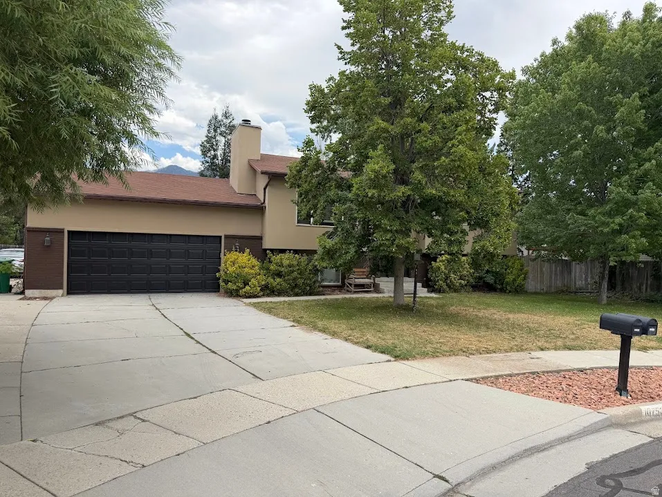 Two-story residence featuring a large front yard with mature trees