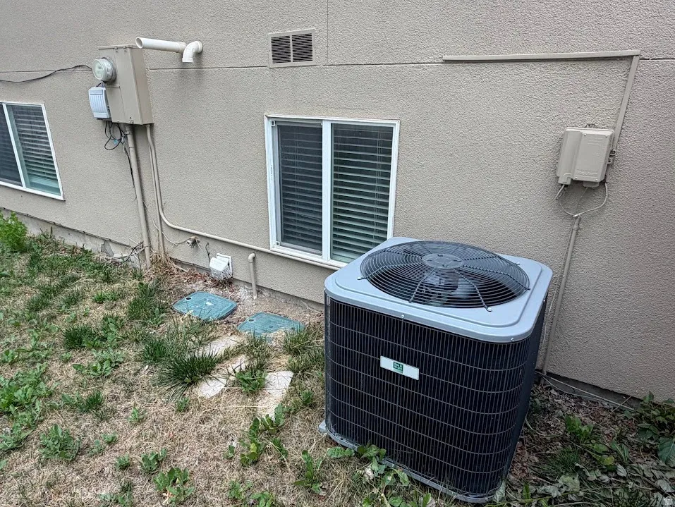 Exterior featuring a stucco finish, two windows, and an outdoor air conditioning unit