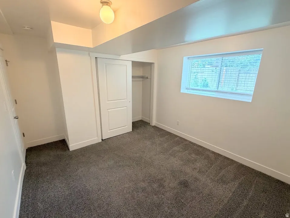 Carpeted room with white walls, a single window, and a sliding two-panel closet door