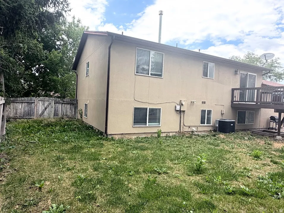 Rear exterior featuring a tan stucco finish, multiple windows, and a raised wooden deck