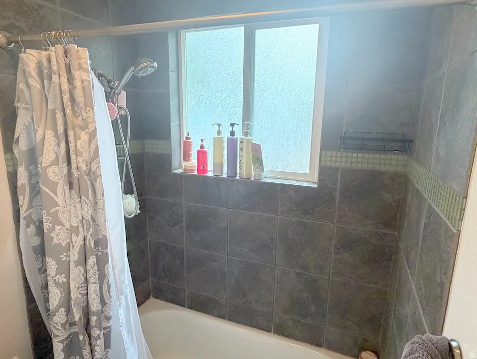 Tiled shower surround featuring a frosted window, a mosaic accent band, and a built-in shower niche
