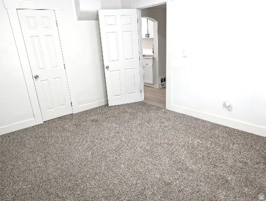 Neutral-toned carpeting extends throughout the room, complemented by white walls and trim