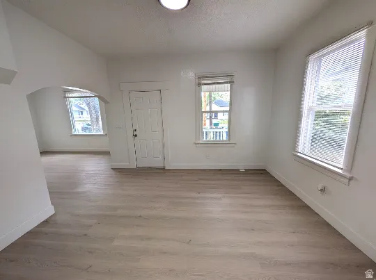 Spacious room featuring wood-finish flooring, white baseboards, and bright white walls