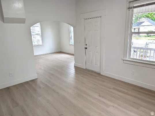 Spacious interior featuring wood-finish flooring, white baseboards, and bright white walls