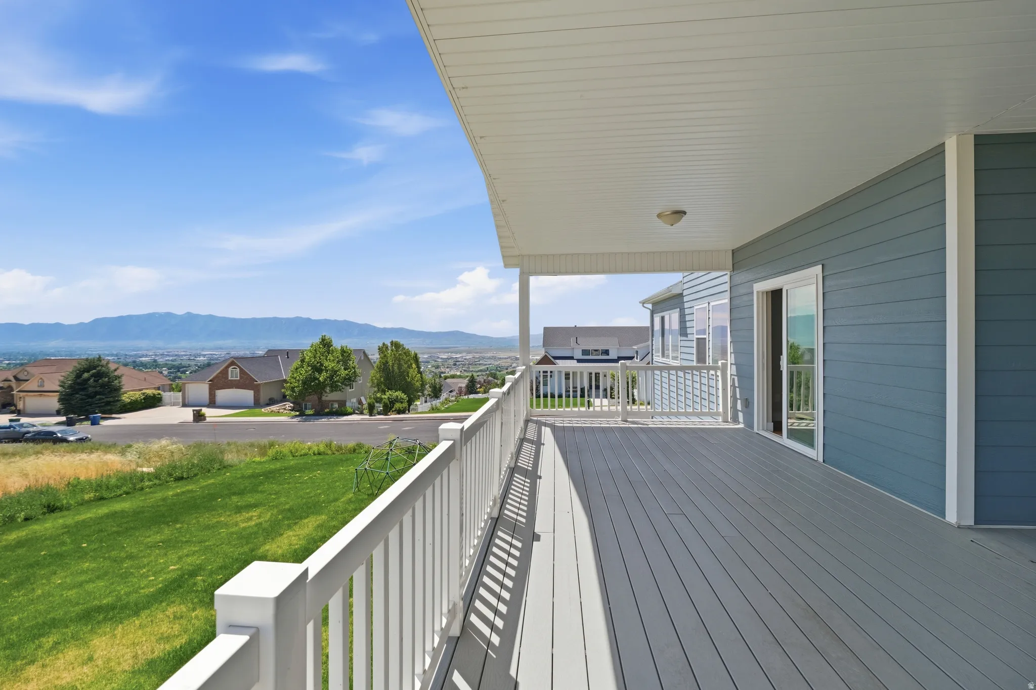 Expansive covered deck with gray composite decking and white railing, offering distant mountain scenery