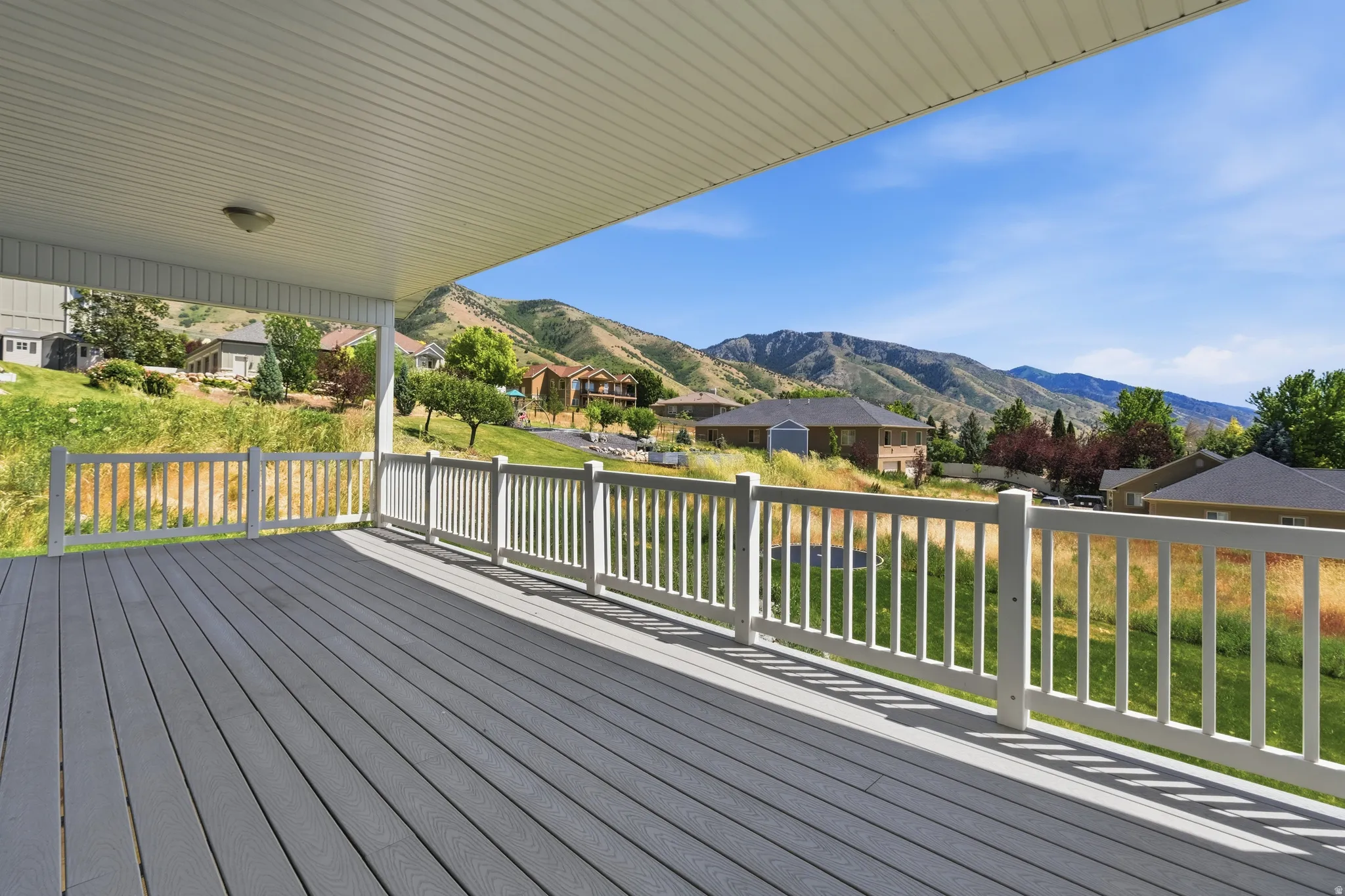 Covered outdoor deck with grey composite decking and white railings