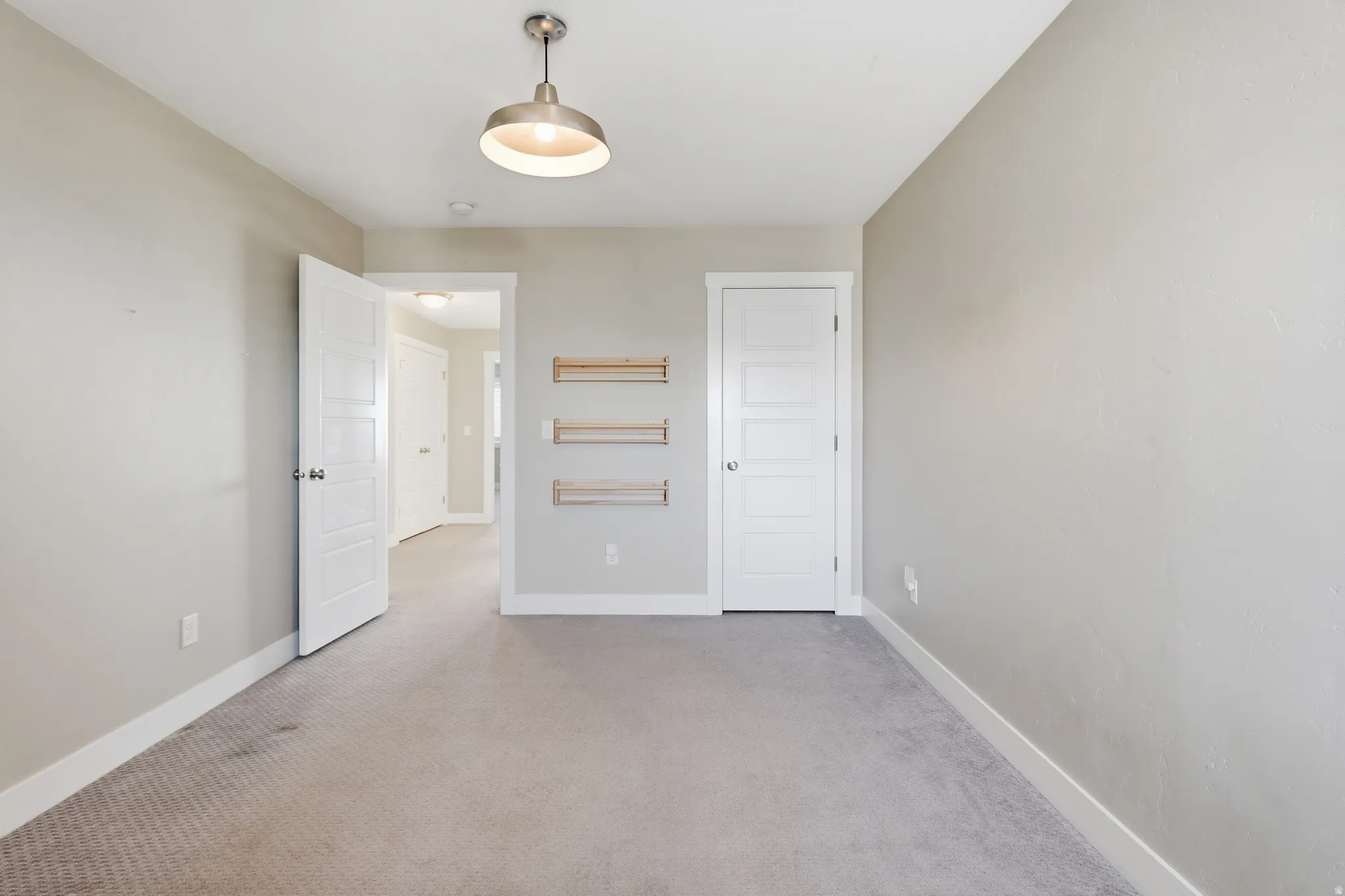 Neutral-toned room with carpet flooring and an industrial-style ceiling light fixture