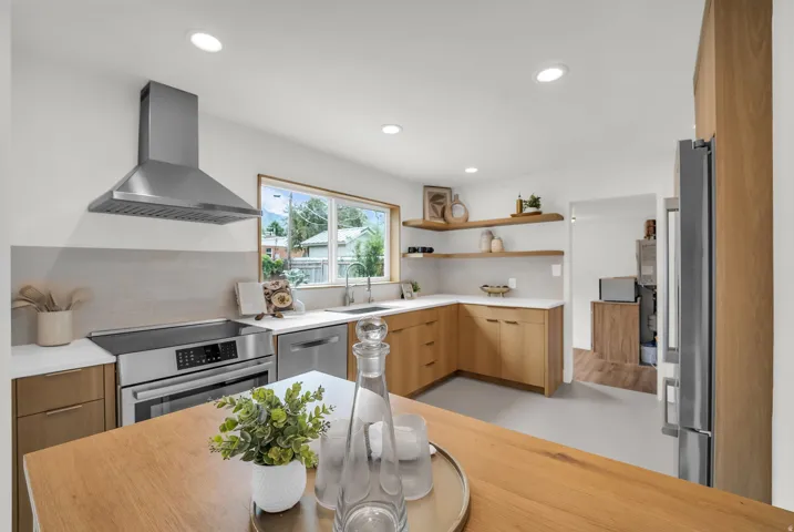 Modern kitchen featuring light wood-finish cabinetry, white countertops, and stainless steel appliances