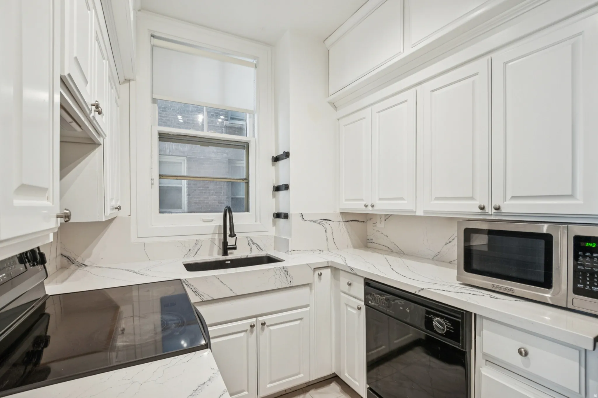 Updated kitchen featuring white cabinetry, integrated sink, black matte faucet, countertops