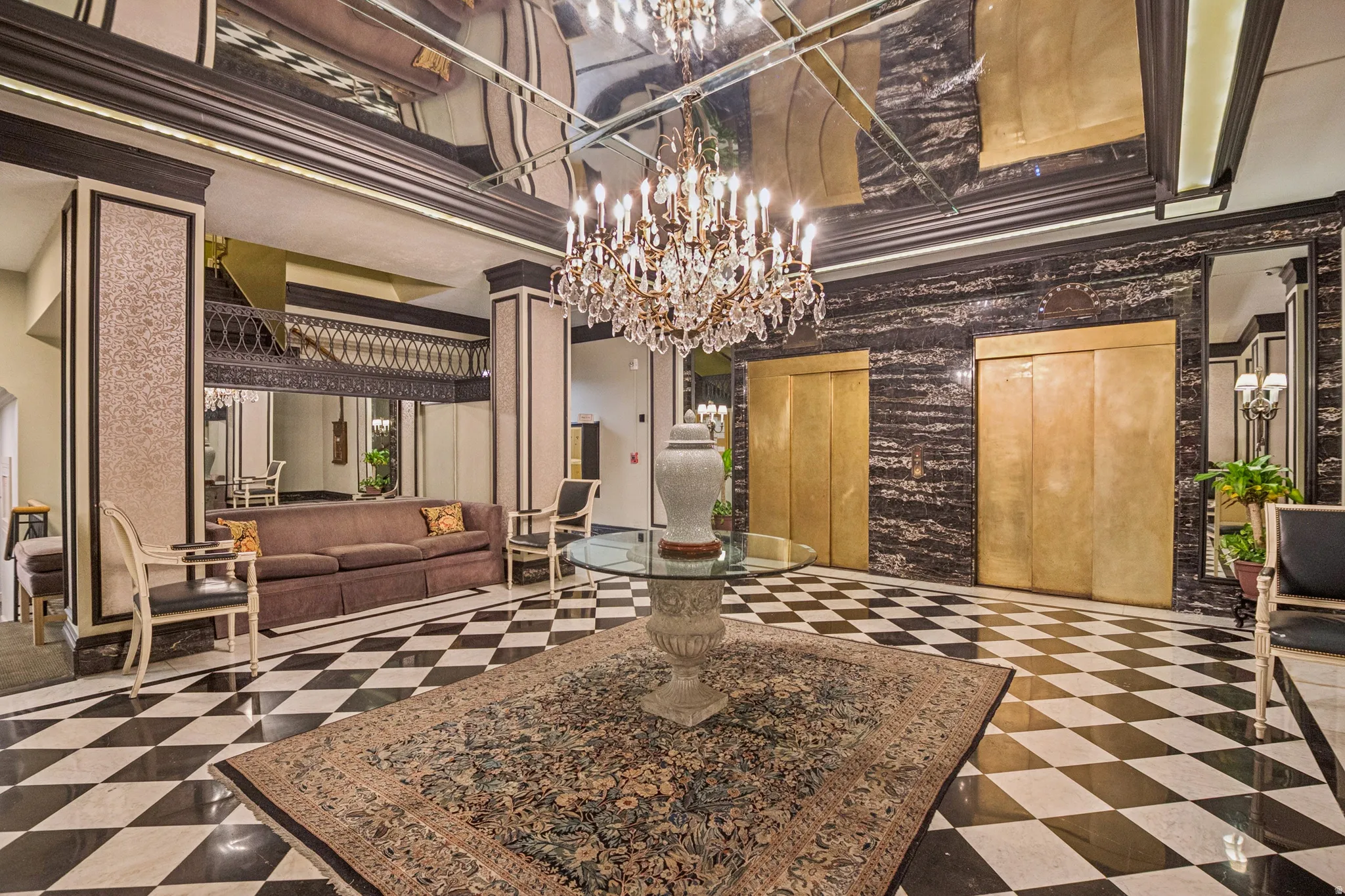 Grand foyer featuring a black and white checkered floor, crystal chandelier, and mirrored ceiling accents