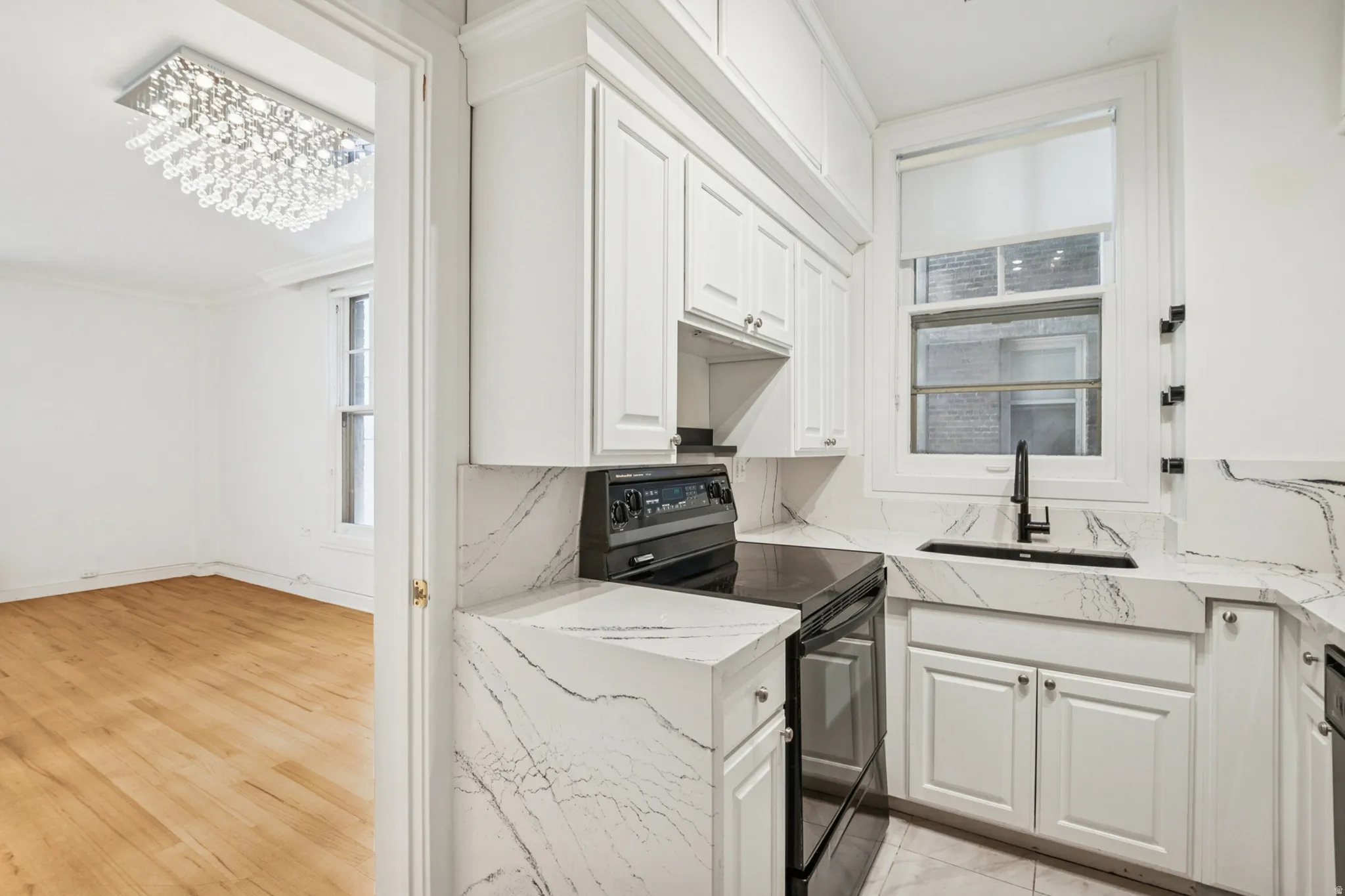 Updated kitchen featuring white cabinetry, integrated sink, black matte faucet, countertops