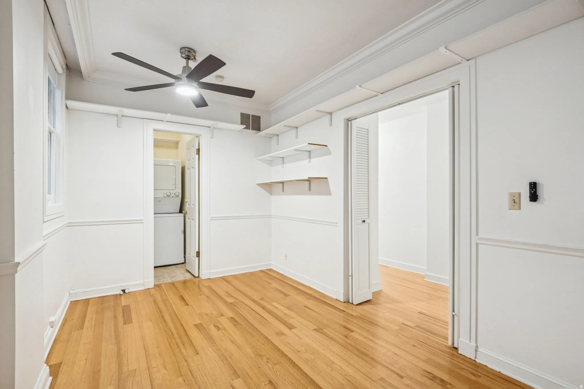 Bedroom 1 featuring hardwood flooring, white walls, and a ceiling fan
