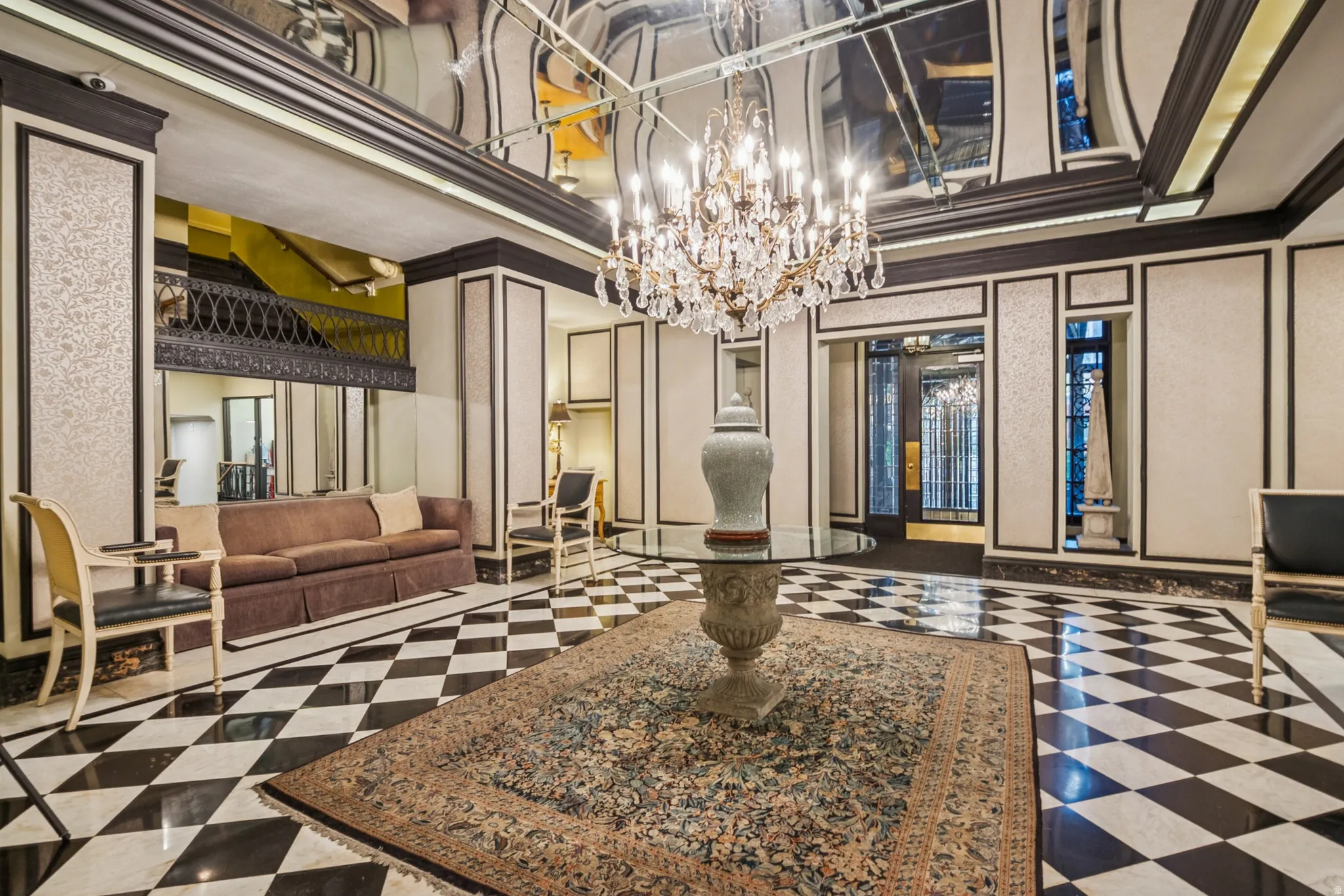 Grand entry foyer featuring a large crystal chandelier, reflective ceiling, and a black and white checkerboard floor