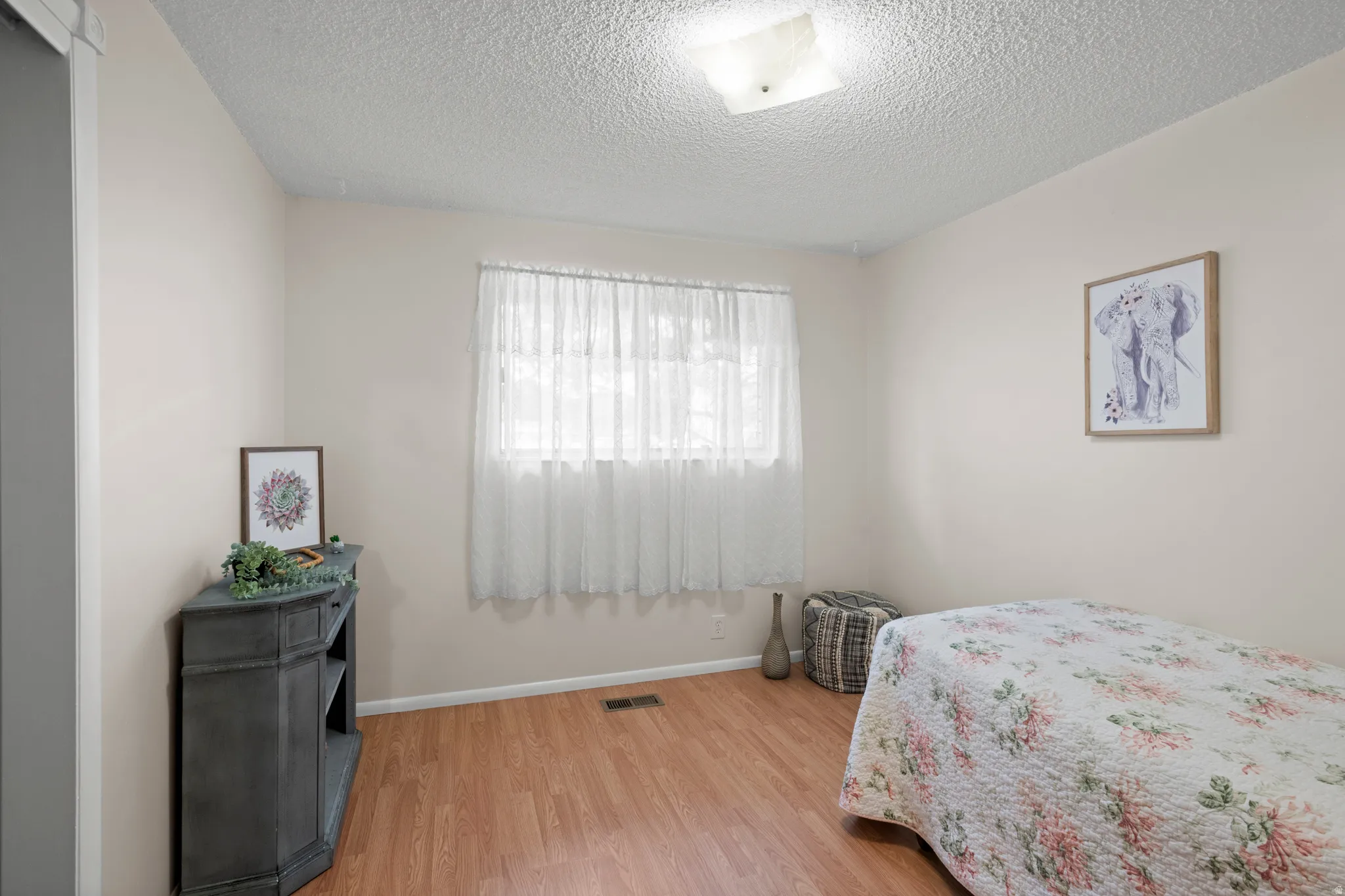 Room featuring wood-finish flooring, a single window, and a ceiling-mounted light fixture