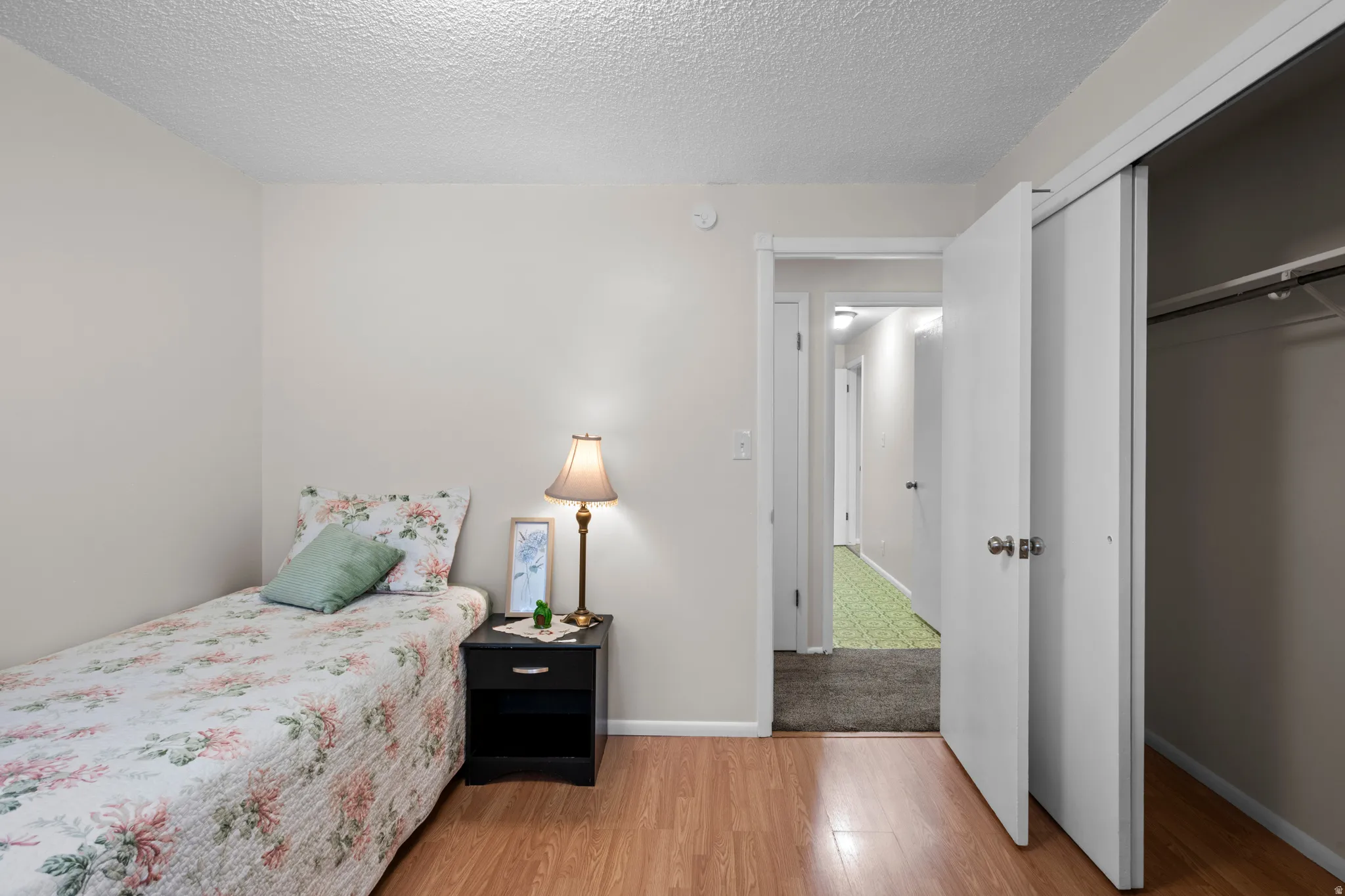 Bedroom featuring wood-finish flooring, a neutral wall color, and a built-in closet with sliding doors