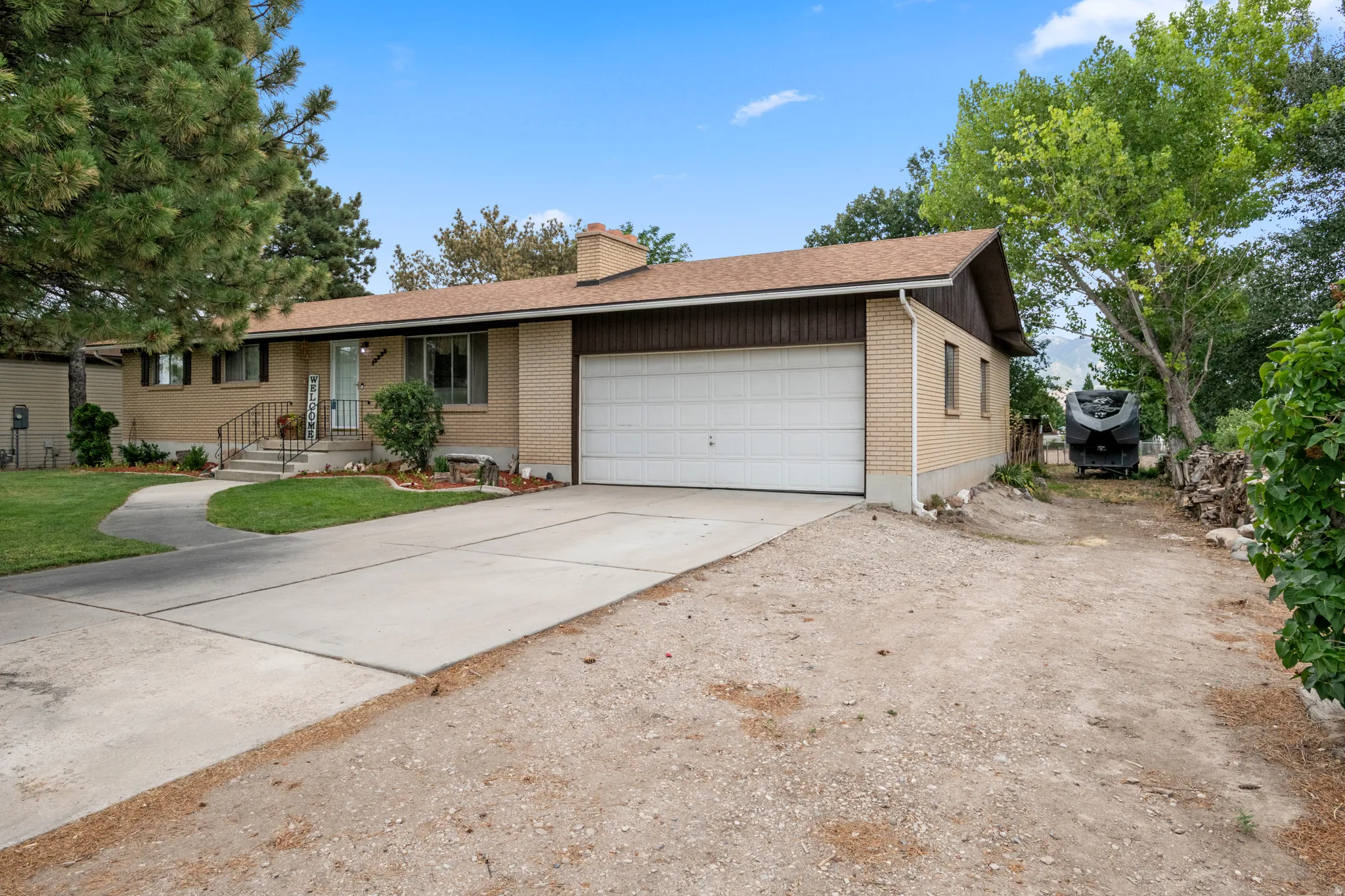 Ranch-style exterior featuring a light brick facade and a multi-car driveway