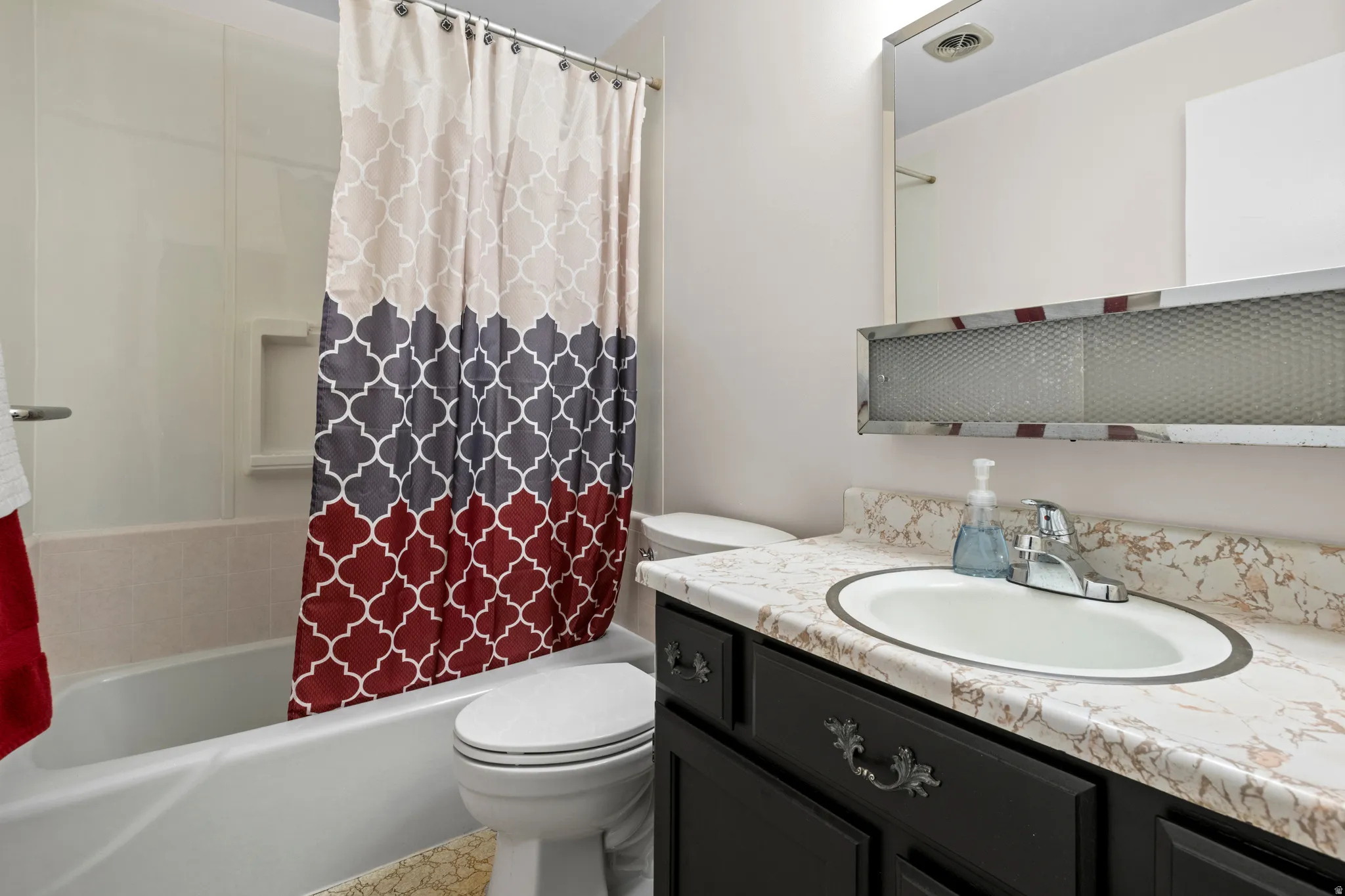 Bathroom featuring a white bathtub, built-in shower niche, and a vanity with a drop-in sink