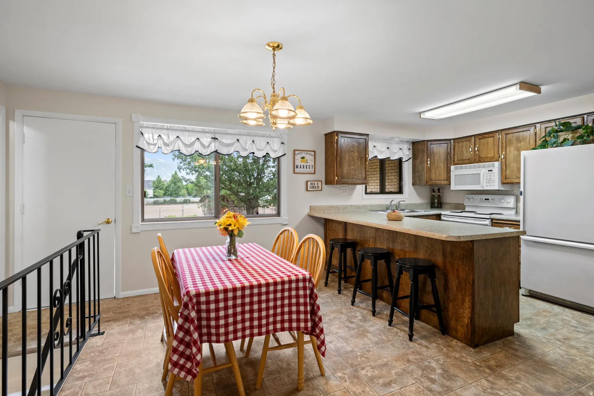 Kitchen featuring wood-finish cabinetry, white appliances, and a breakfast bar with built-in seating