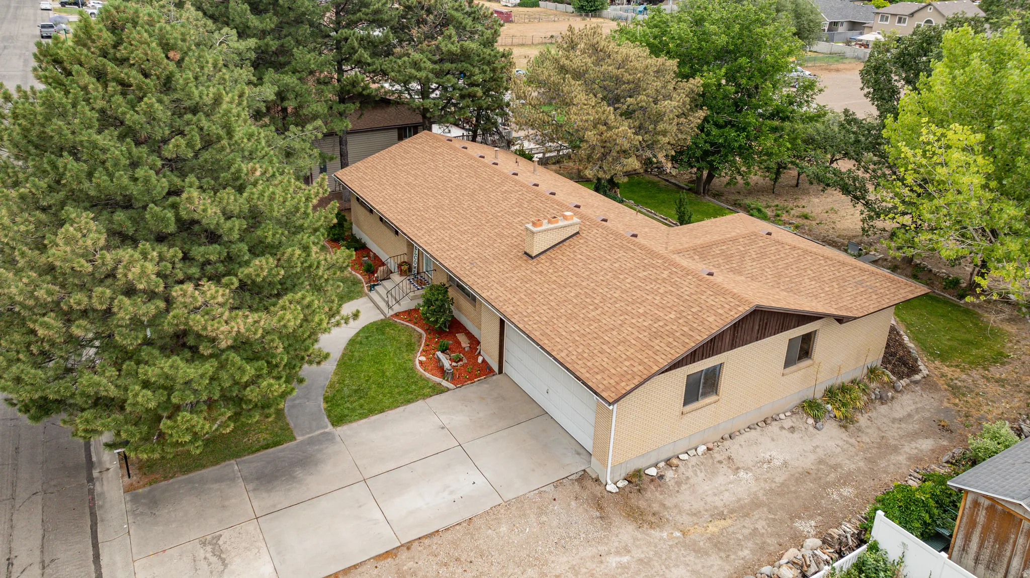 Tan brick exterior with a brown shingle roof