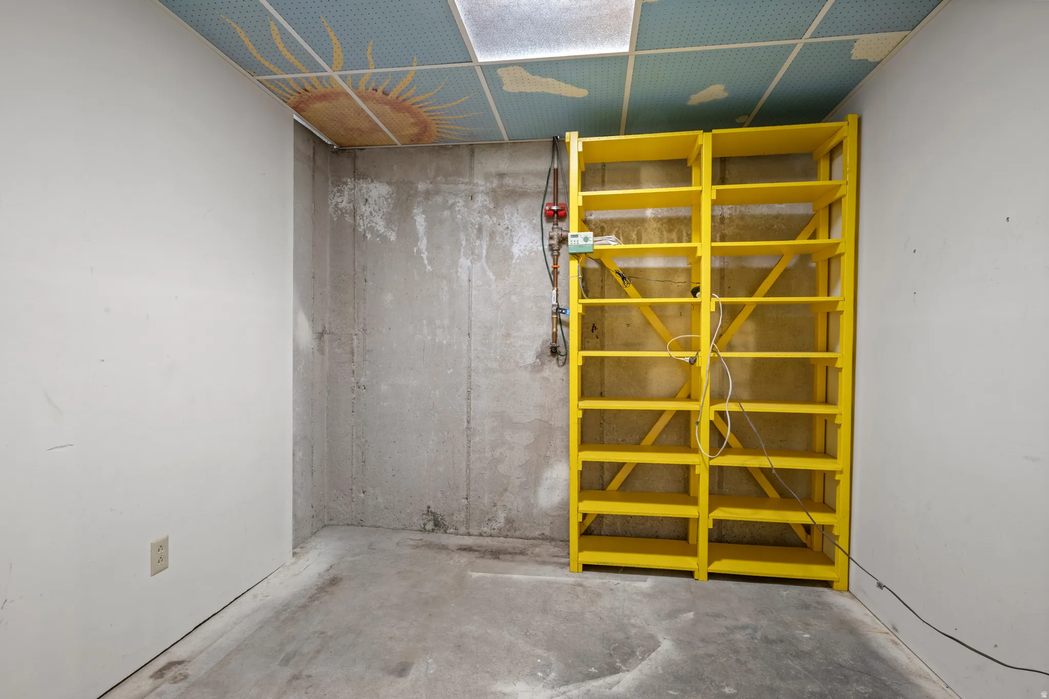 Concrete flooring with a dropped ceiling featuring a sun motif