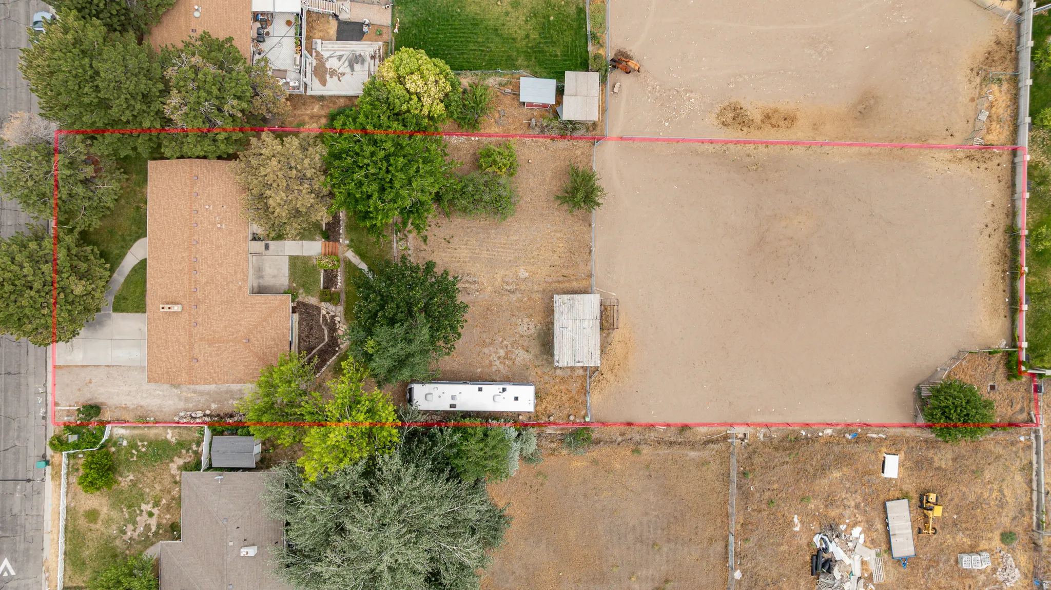 Expansive lot featuring a single-story residence with a brown shingle roof, mature perimeter trees, a concrete driveway.