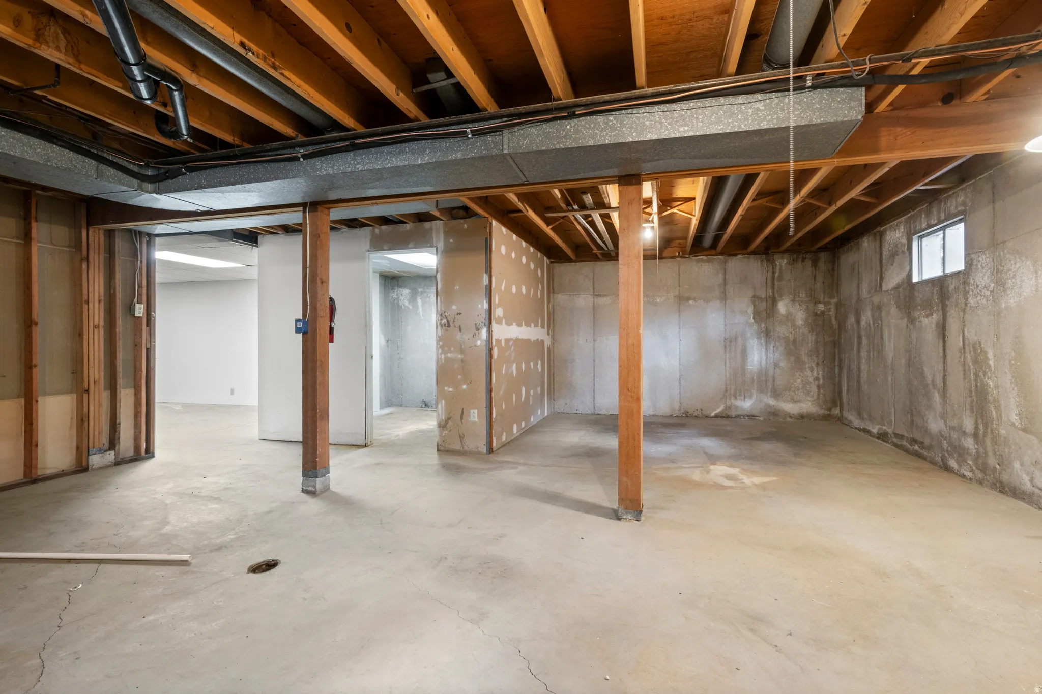 Unfinished basement featuring exposed wood ceiling joists, concrete flooring, and partial wall framing