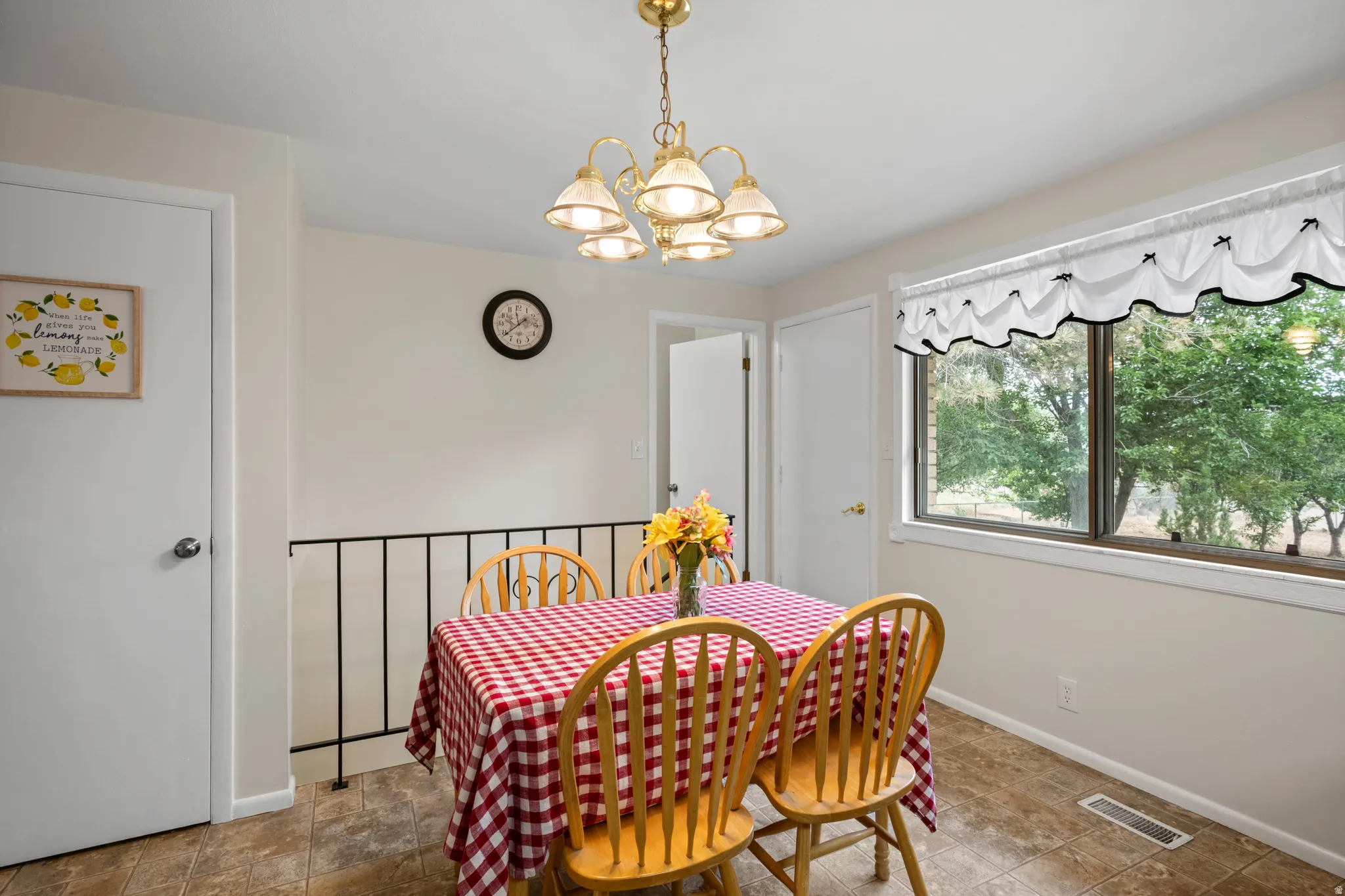 Dining area featuring a brass chandelier, large window, and tile flooring