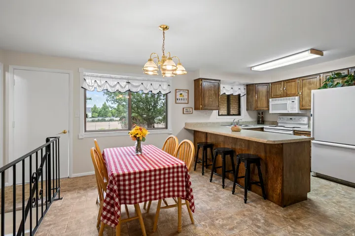 Kitchen featuring wood-finish cabinetry, white appliances, and a breakfast bar with built-in seating