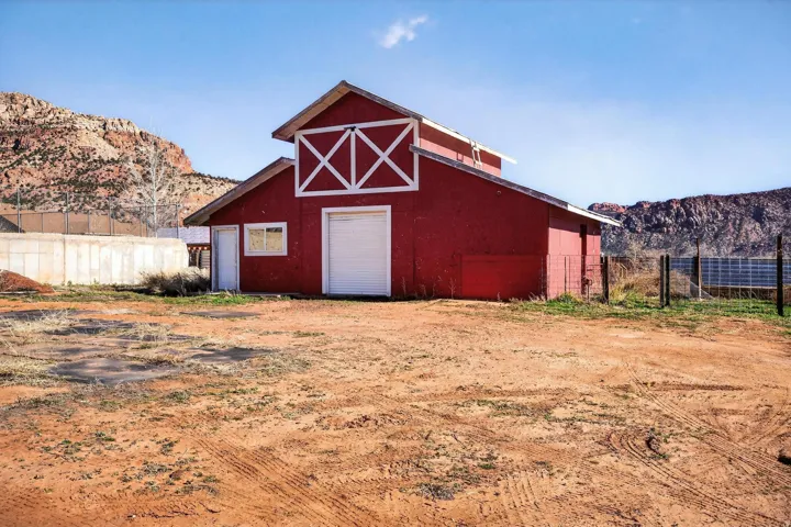 Red barn structure featuring a prominent white crossbuck design on the gable
