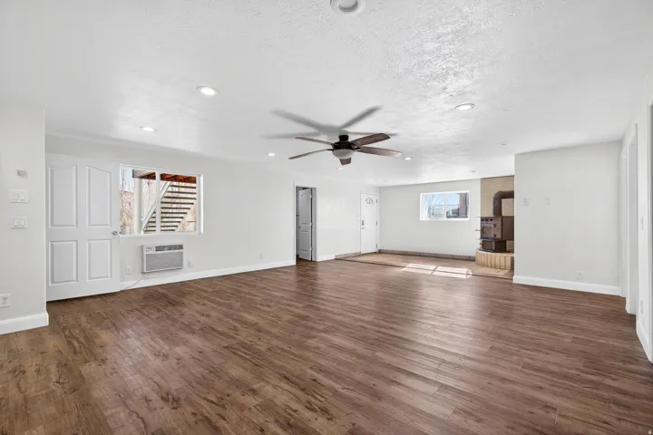 Spacious room featuring wood-finish flooring, recessed lighting, and a ceiling fan