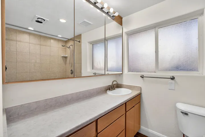 Bathroom featuring a vanity with a drop-in sink, brushed nickel faucet, wood-finish cabinetry, and a full-width mirror