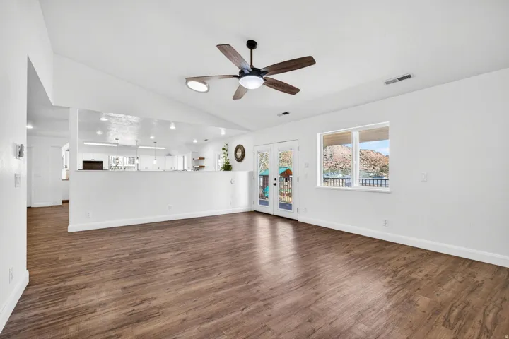 Open-concept living area featuring wood-finish flooring, vaulted ceilings, and a ceiling fan with integrated lighting