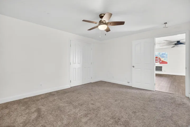 Spacious room featuring neutral carpeting and a ceiling fan