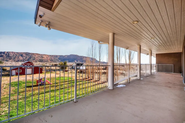 Expansive covered patio featuring concrete flooring and a white metal railing
