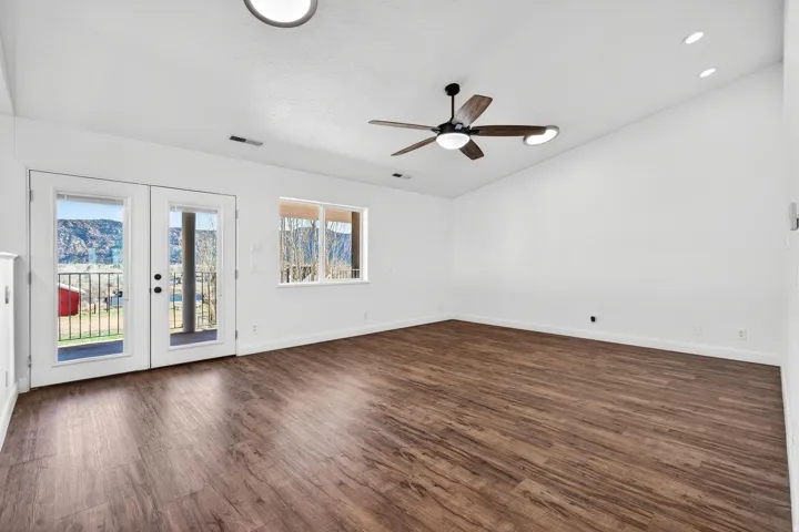 Spacious room featuring wood-finish flooring, vaulted ceilings, and a modern ceiling fan